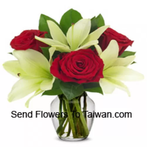 Roses rouges et lys blancs avec des remplisseurs saisonniers dans un vase en verre