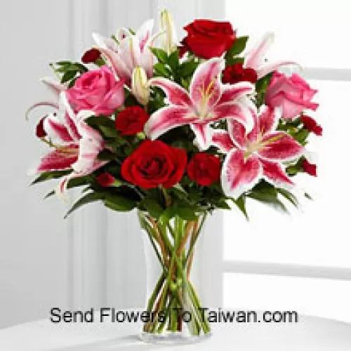 Roses rouges et roses avec des lys roses et des remplissages saisonniers dans un vase en verre